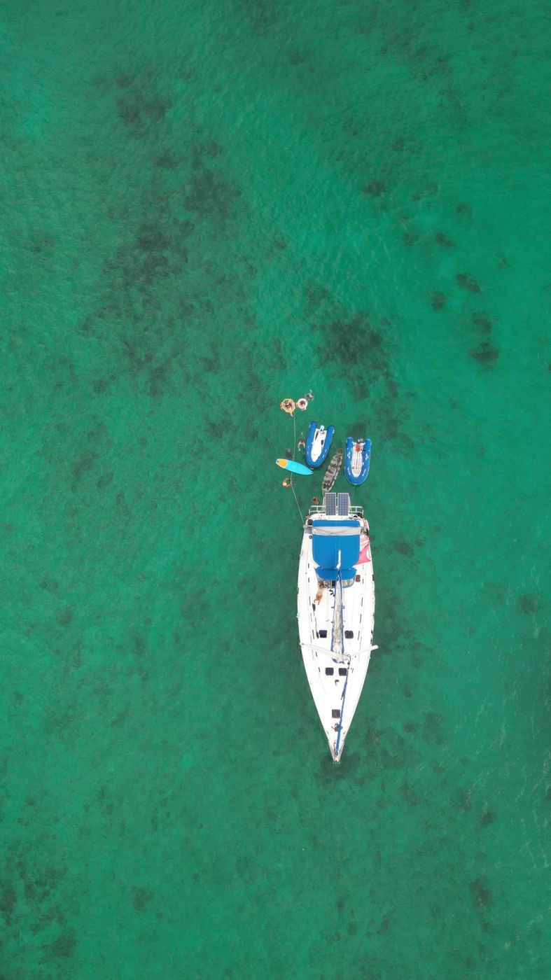 Aerial view of a sailboat over a green reef