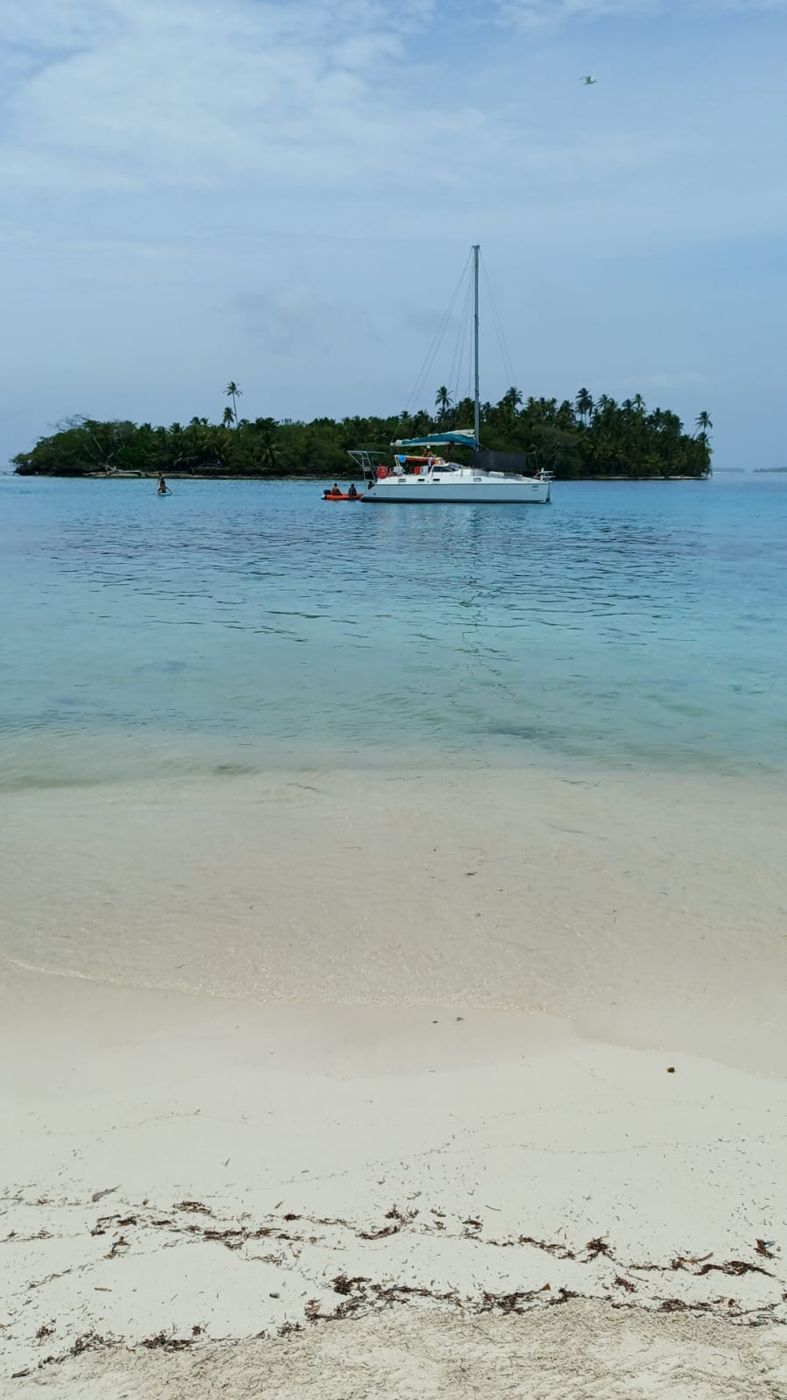 Empty white sand beach with a boat and island behind